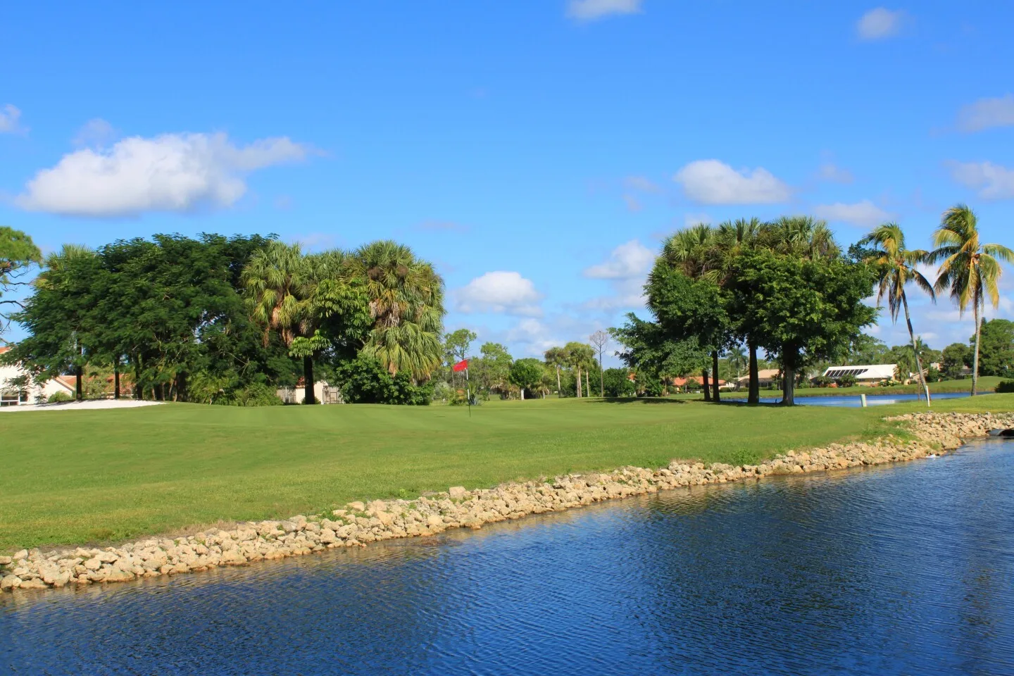 Lake view toward the green at Spanish Wells (official club site).