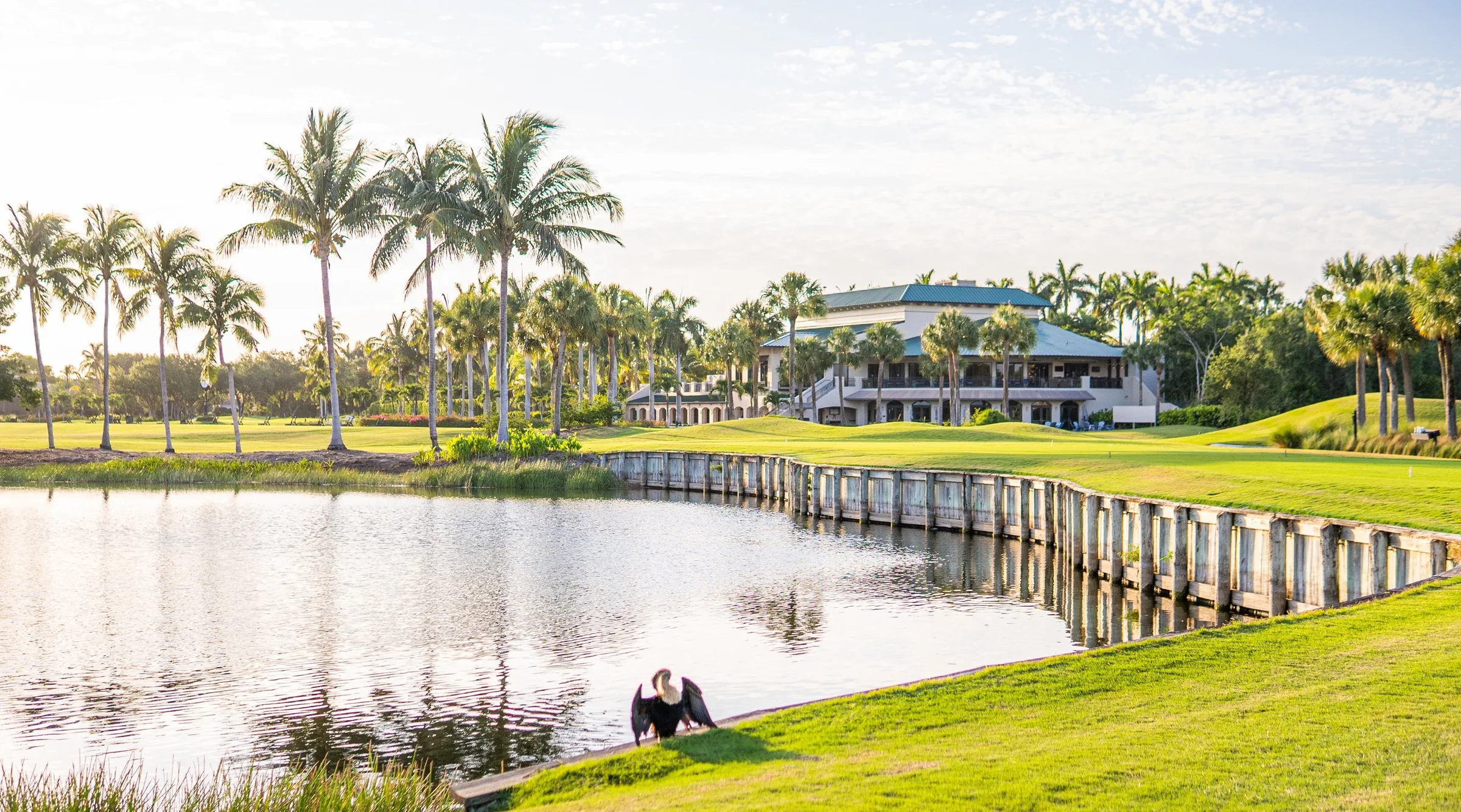 Clubhouse across the lake with footbridge at Pelican Marsh, Naples (official club site).