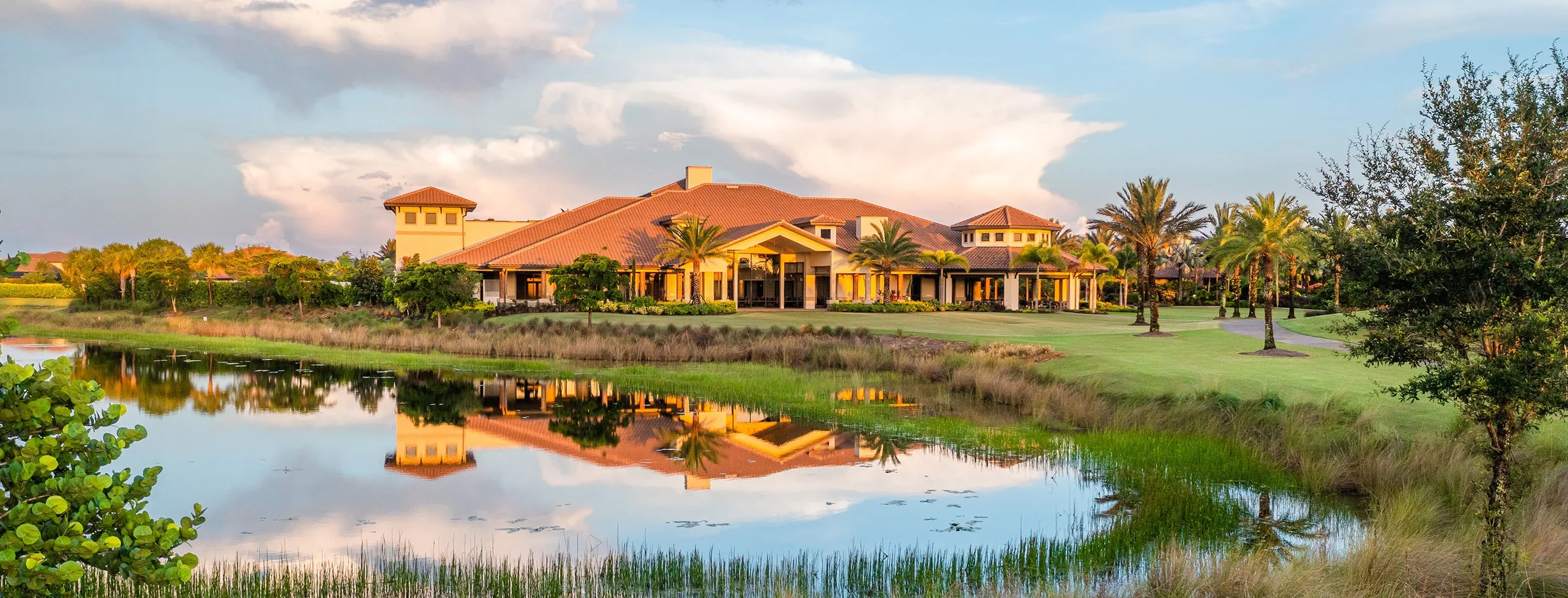 Clubhouse reflected in a lake at sunset, Esplanade Golf and Country Club, Naples (official club site).