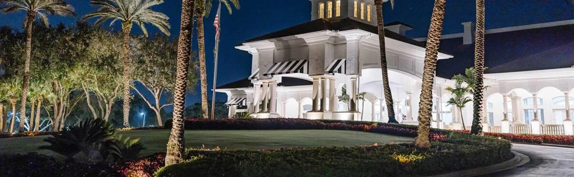 Clubhouse exterior lit at night, The Strand, Naples (official club site).