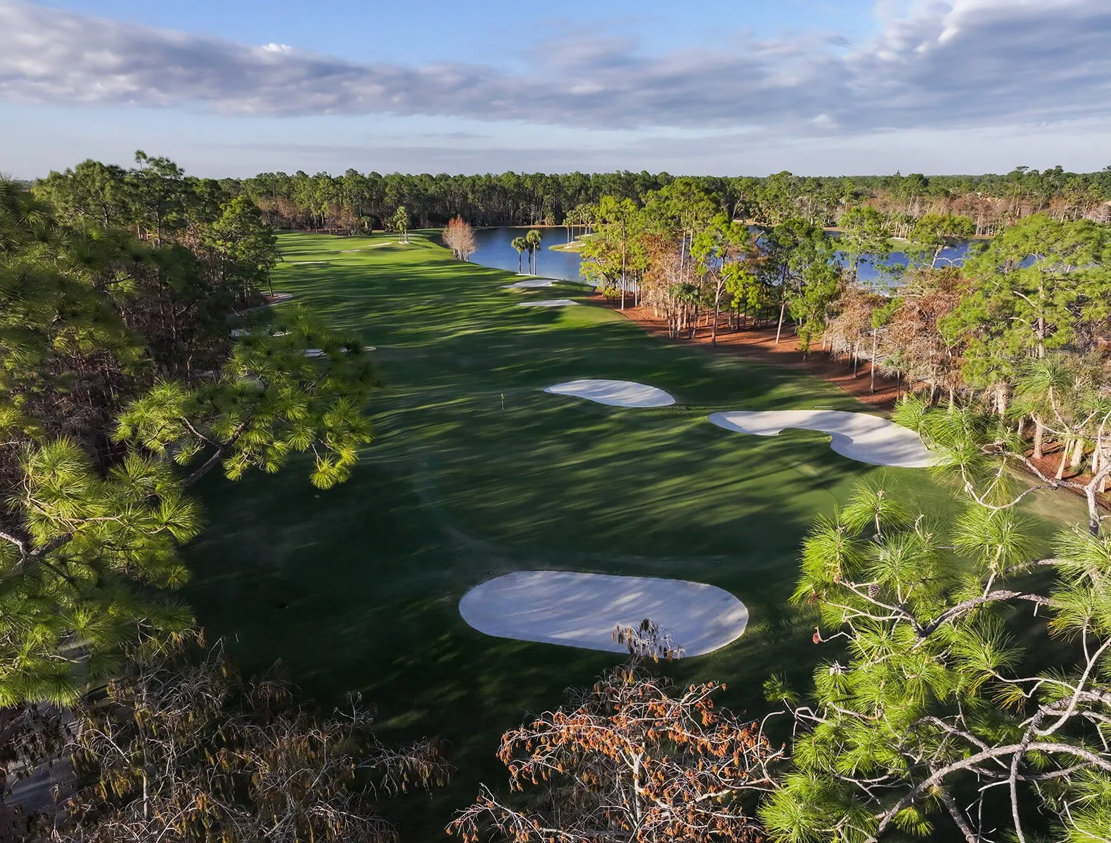 Golf hole with bunkers through the pines at Vanderbilt, Naples (official club site).