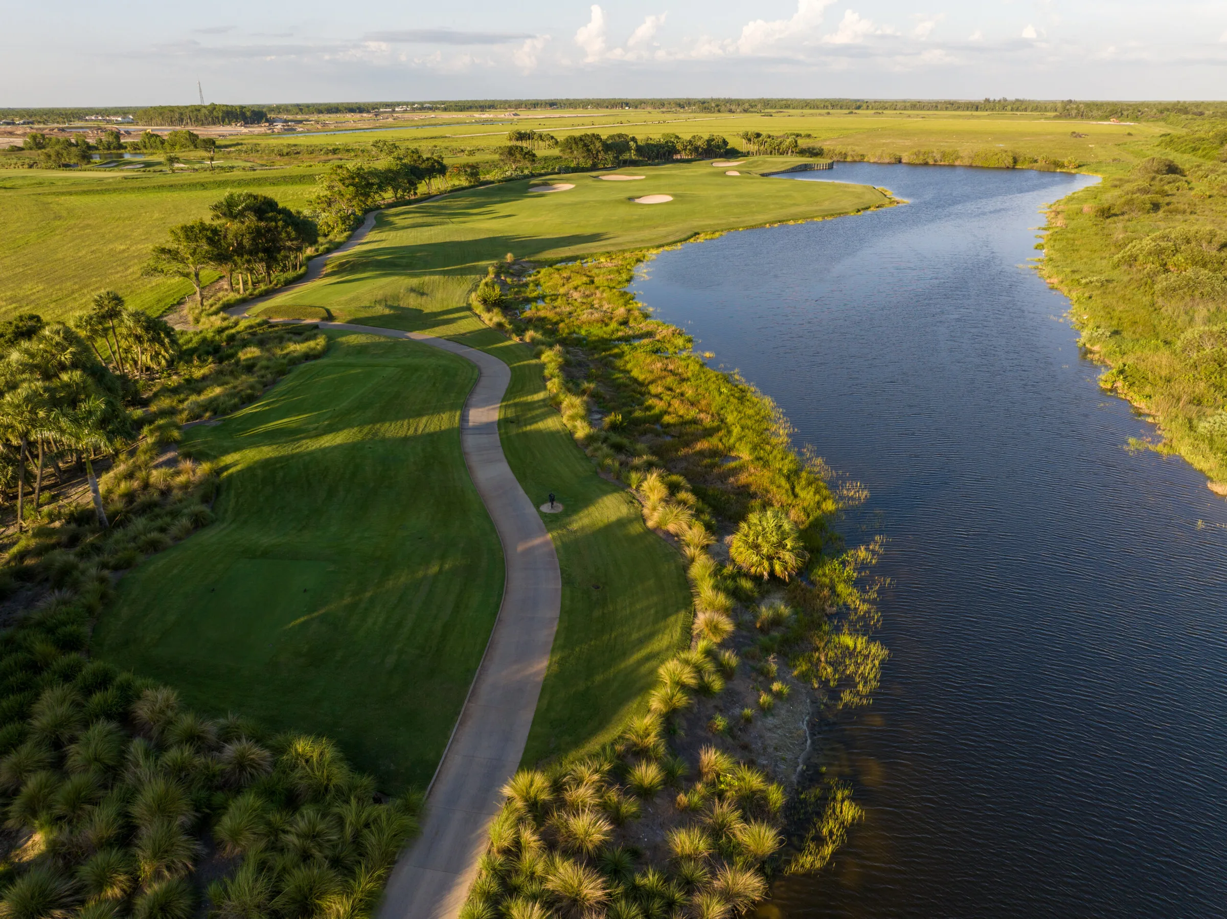 Aerial view of a fairway beside a natural waterway at Fiddler's Creek, Naples.