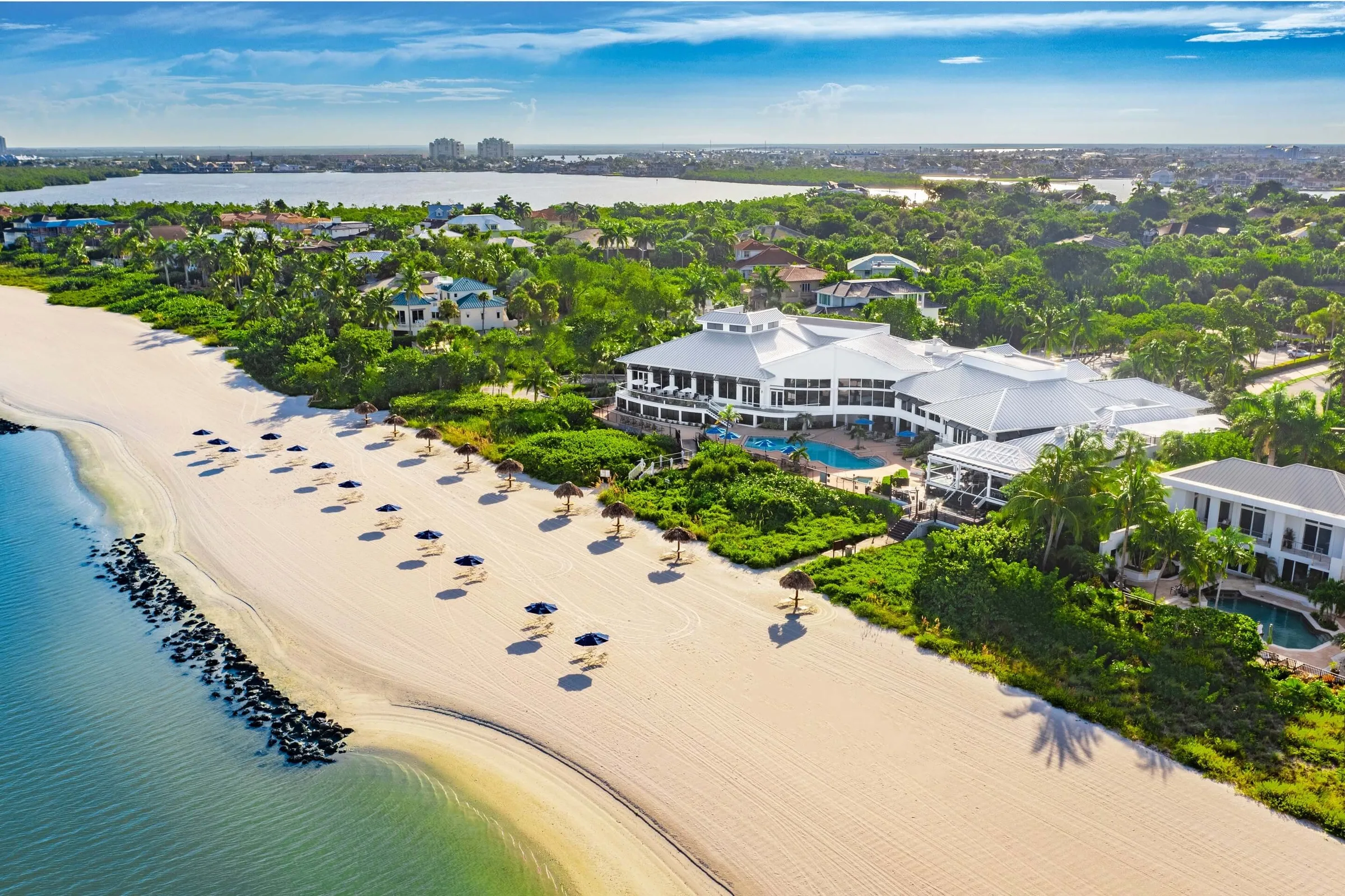 Aerial clubhouse pool and private beach with umbrellas at Hideaway Beach Club, Marco Island (official).