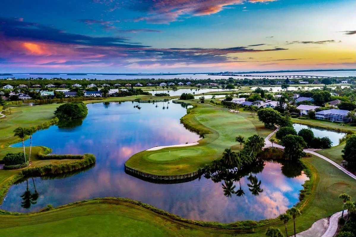 Aerial golf course at dusk with Sanibel Causeway beyond, The Dunes (official).