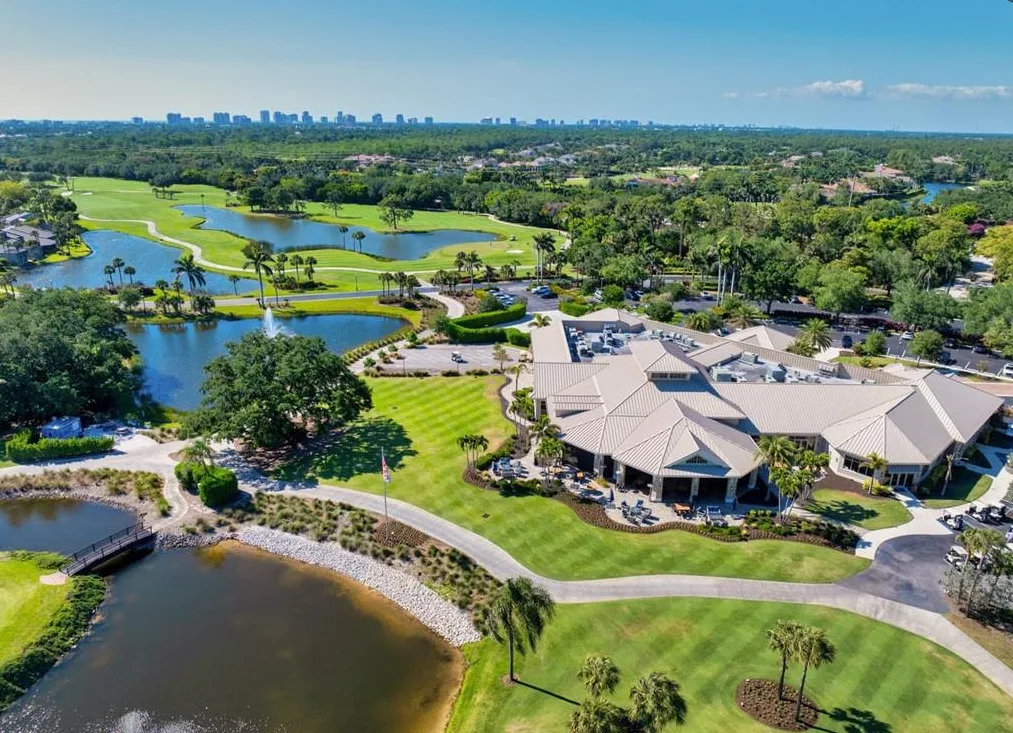 Aerial of the clubhouse and golf course with a lake, fountain and footbridge at Bear's Paw
