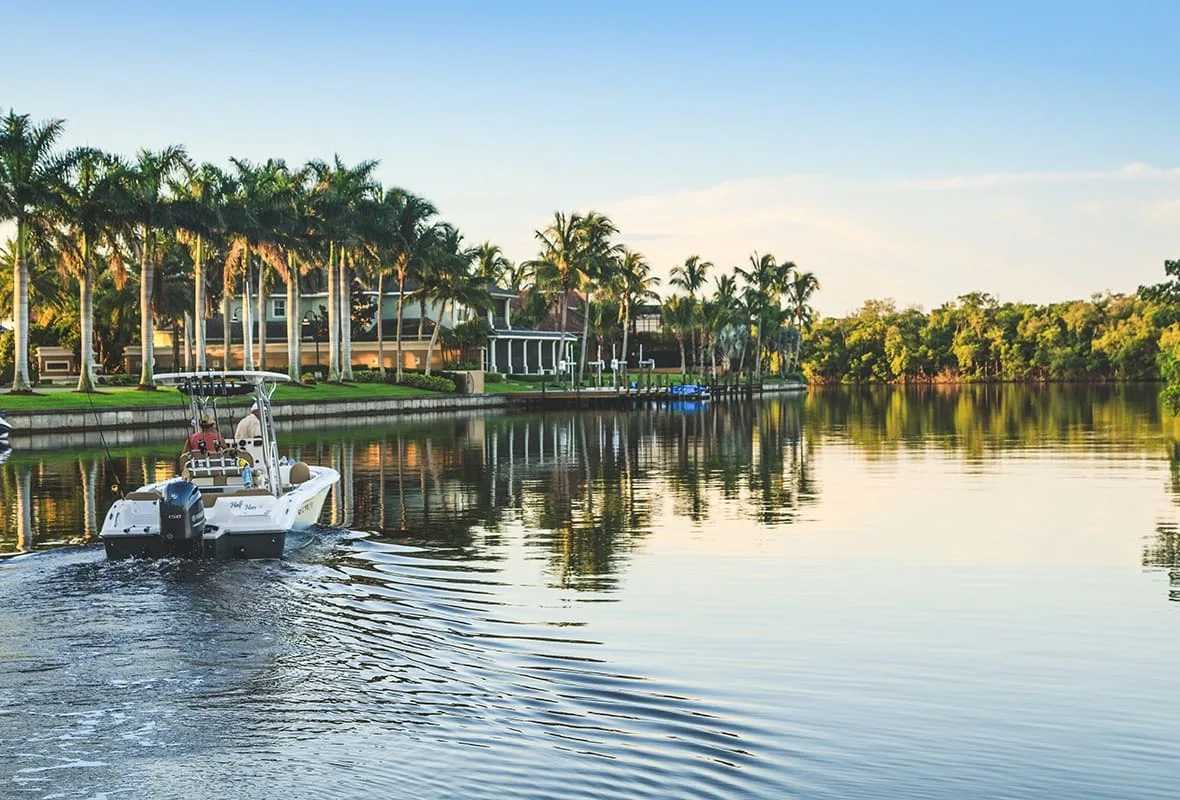 Boat cruising the palm-lined waterway at Cape Harbour, Cape Coral (official Safe Harbor Cape Harbour marina site).