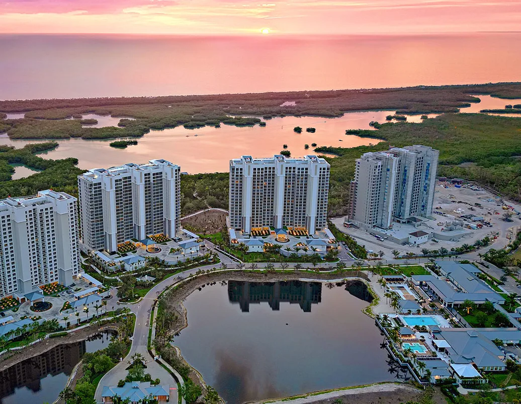 Aerial of the Kalea Bay towers, lake and club at sunset, North Naples
